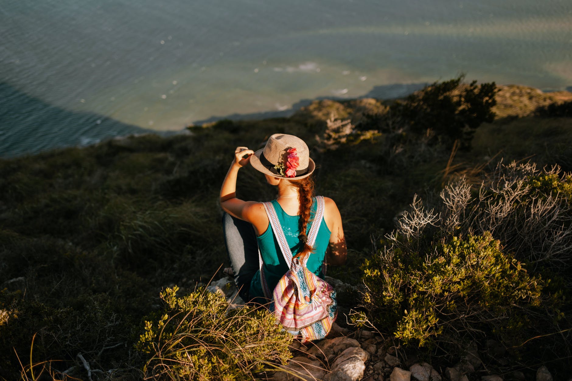 faceless female tourist with rucksack enjoying lake from mount
