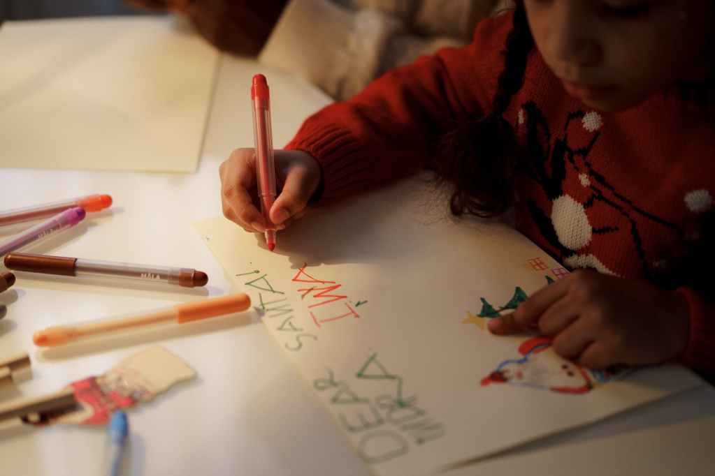 girl in red sweater making a christmas letter