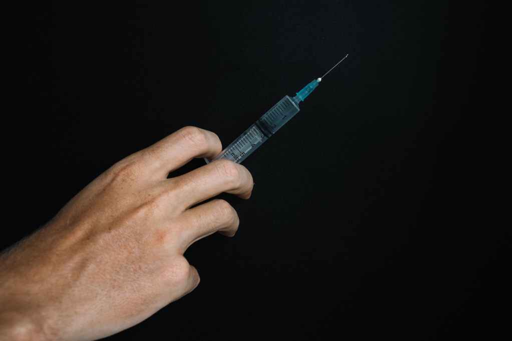 person holding a syringe on black background