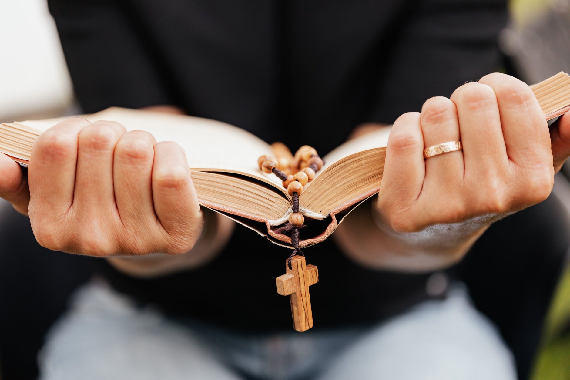 close up shot of a person reading a book with rosary