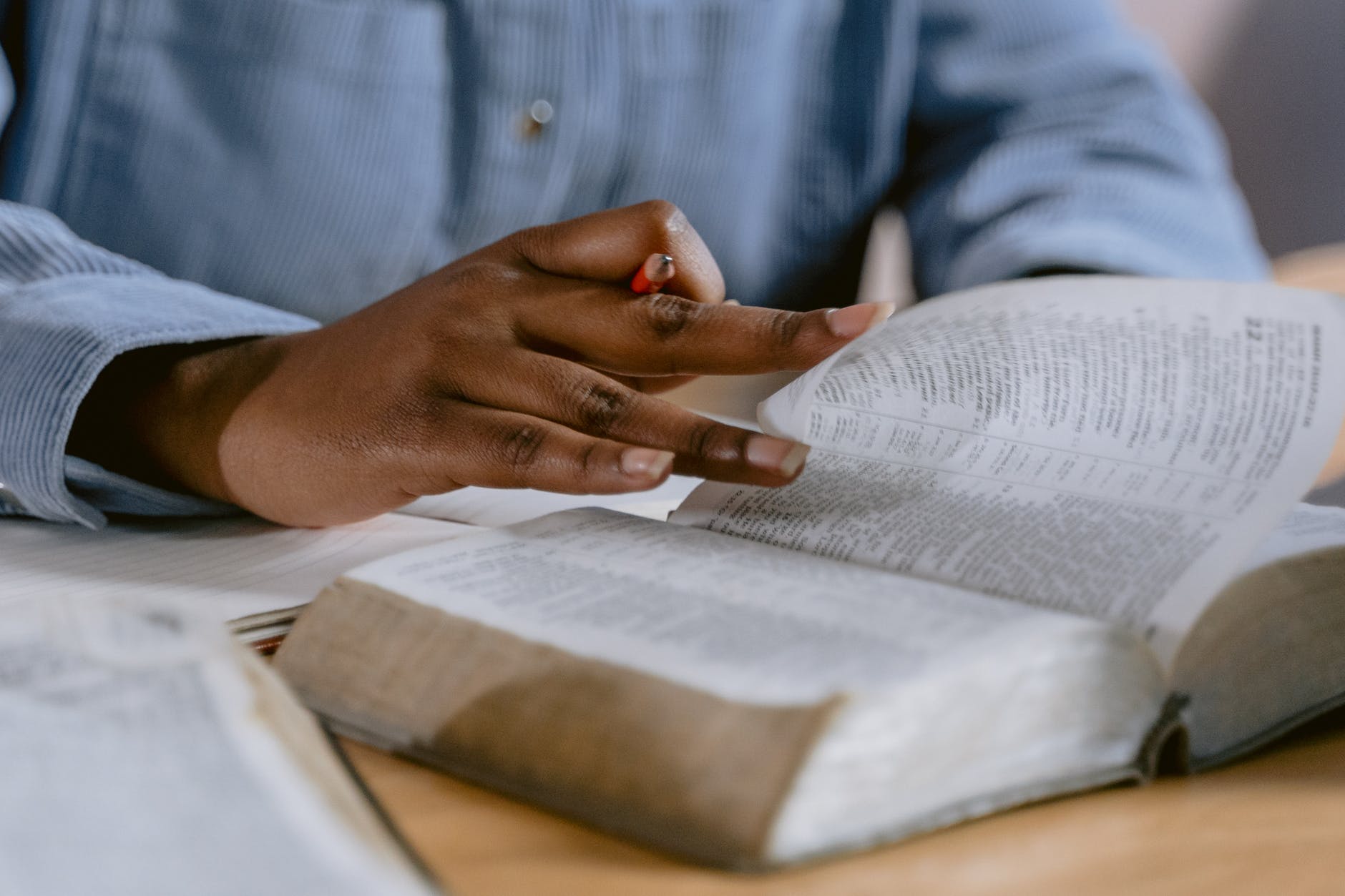 selective focus photo of a person s hand flipping the pages of a book