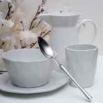 white ceramic cup and saucer beside the teapot