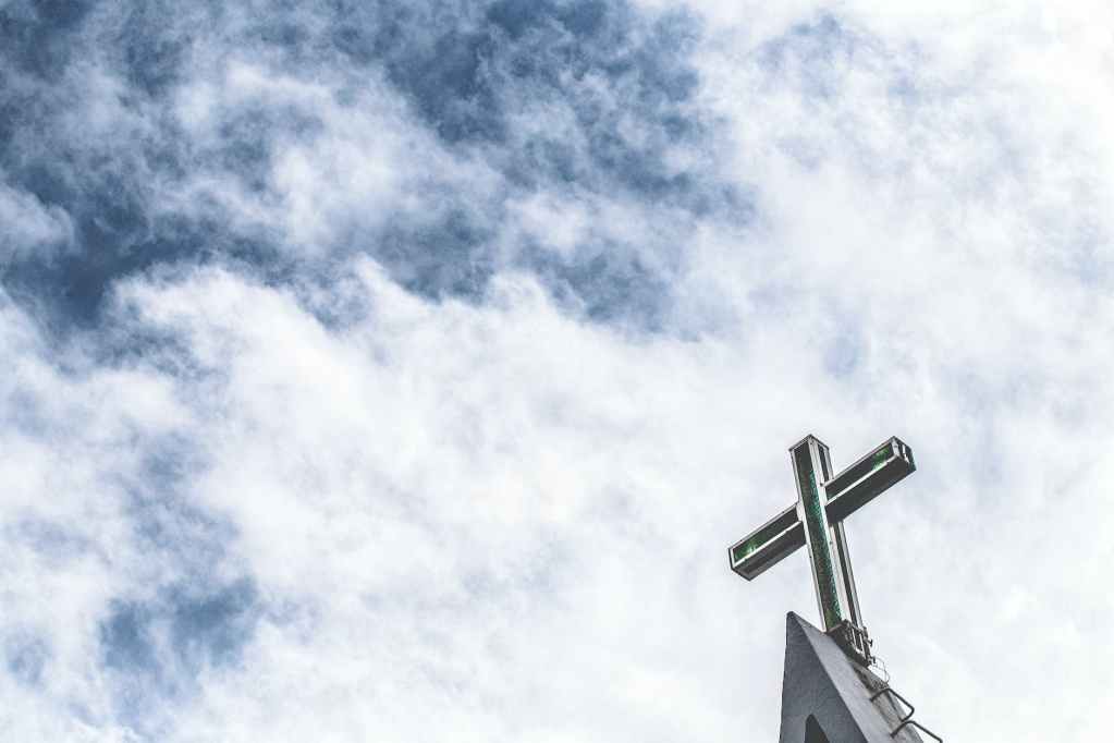 low angle photo of cross under cloudy sky