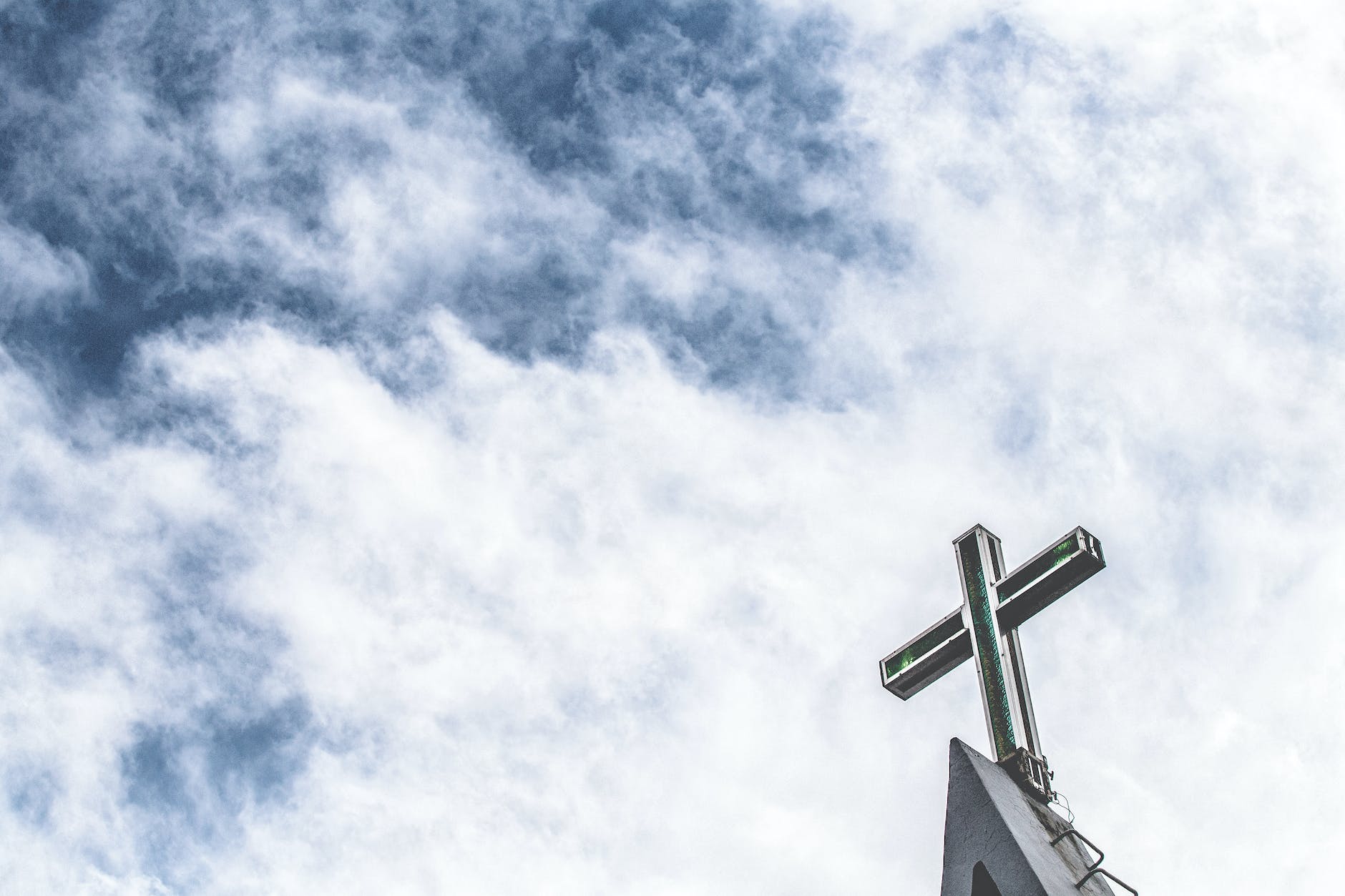 low angle photo of cross under cloudy sky