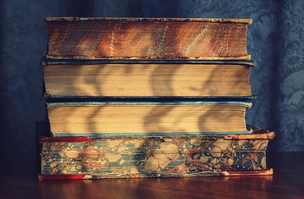 four pile of books on top of brown wooden surface