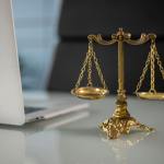 a golden balance scale beside a laptop