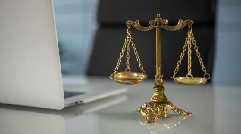 a golden balance scale beside a laptop