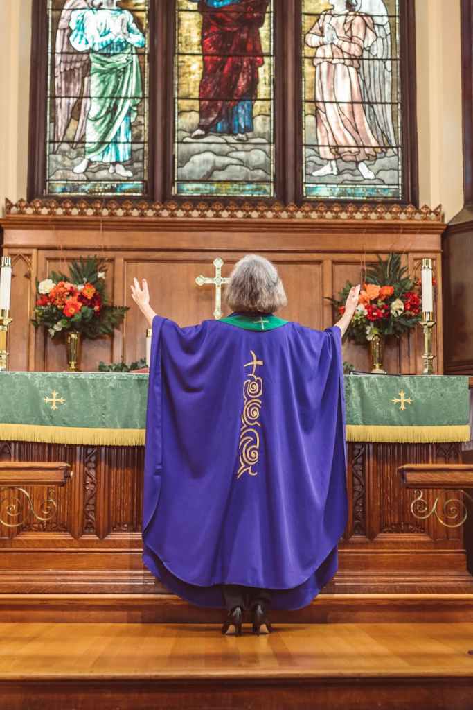 priestess with hands raised standing on the altar